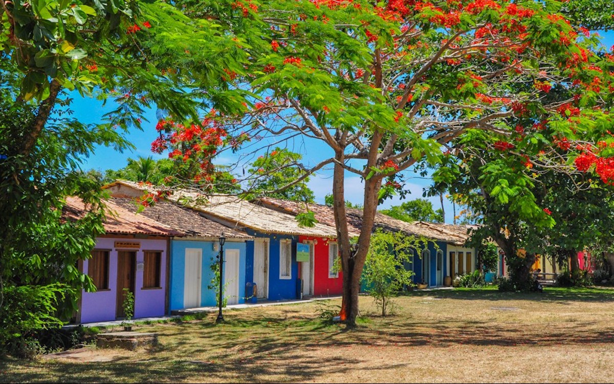 Pequena vila cercada por montanhas e natureza, sem turistas, representando um destino tranquilo.